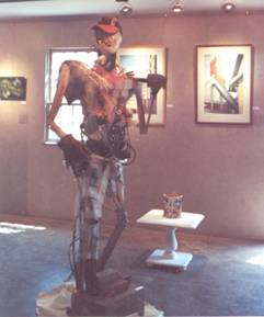 Constructed Worker by Mitch Gordon, composed of found scrap building materials and baseball cap donated by painter Jerome Gonsalves.  In background are works by Bob Kimberly and Peter Hussey.